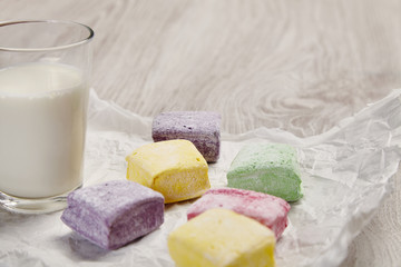 Colored marshmallows on wooden white table with milk side view