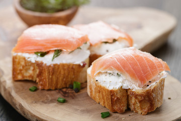 baguette slices with soft cheese and salmon on wood table