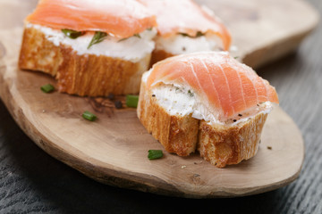 baguette slices with soft cheese and salmon on wood table