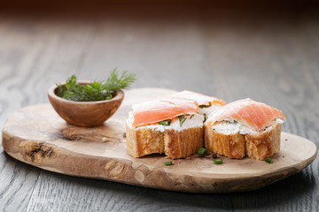 baguette slices with soft cheese and salmon on wood table