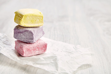 Column from three pastel marshmallows on white craft paper