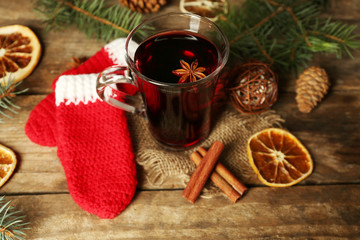 Christmas composition of mulled wine, cinnamon, pine and red knitted mittens on wooden background