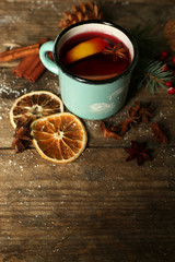 Decorated composition of mulled wine in mug on wooden table