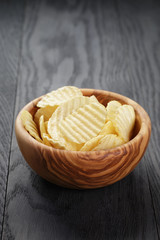 bowl full of salted potato ships on old wooden table