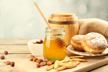 Glass jar with honey, honeycombs and nuts on wooden background