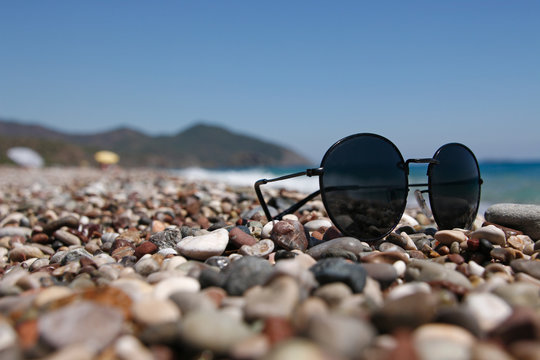 Sunglasses on a pebble beach by the sea.