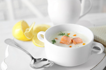 Delicious salmon cream soup on white decorated with lemon and cotton serviette table in the restaurant