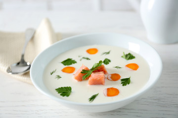 Delicious cream soup with salmon and carrot in white bowl