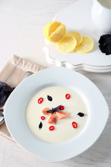 Delicious cream soup with fish and basil on white served table in the restaurant