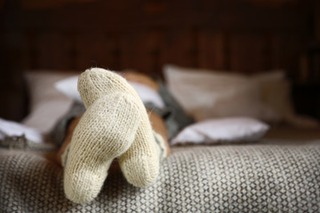 Fototapeta na wymiar Legs of woman in warm socks on bed