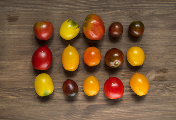 Different varieties of tomatoes on wooden background