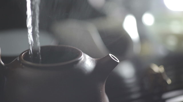 The action of brewing Chinese tea. Water pouring into clay teapot. Asian traditional tea ceremony. Ancient customs of leisure.