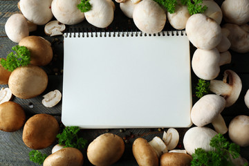 Fresh mushrooms and empty notebook on wooden background © Africa Studio