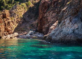 Fototapeta premium rocky island wall above azure sea with small buildings in gorge