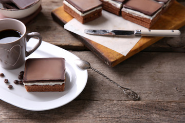 Delicious chocolate brownies on plate and coffee mug, on wooden background