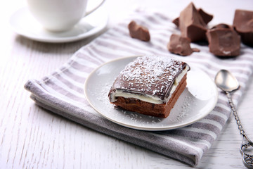 Delicious chocolate brownie on plate on wooden background