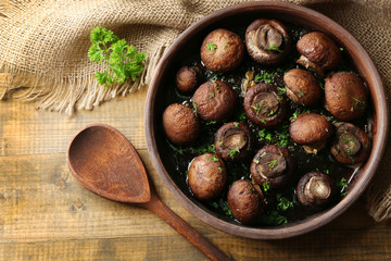Obraz premium Baked champignons mushrooms with butter, parsley and roasted garlic in brown bowl