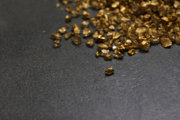 A pile of Gold nugget grains, on cement background