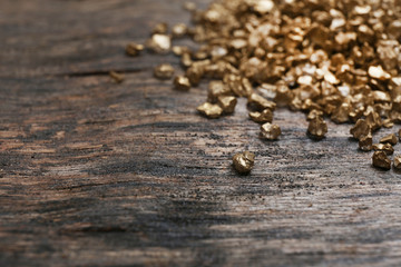 A pile of Gold nugget grains, on wooden background