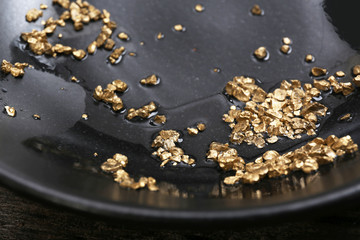 Gold nugget grains, on black plate, close-up