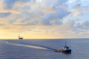 Fototapeta premium Offshore jack up drilling rig and supply boat in the middle of t