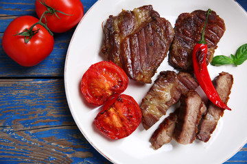 Roasted beef fillet and grilled vegetables on plate, on wooden background