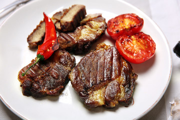 Roasted beef fillet and grilled vegetables on plate, on wooden background