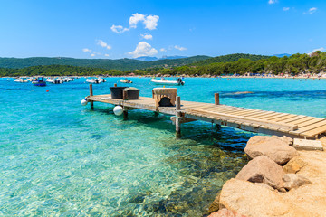 Wooden jetty and azure sea water of Santa Giulia bay, Corsica island, France