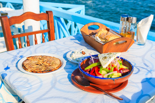 Greek salad on table in traditional tavern with blue sea water in background on Samos island, Greece