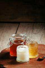 Three types of honey in jars on an old wooden table, selective f