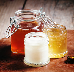 Three types of honey in jars on an old wooden table, selective f