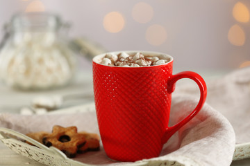 A cup of tasty cocoa and marshmallow on blurred background