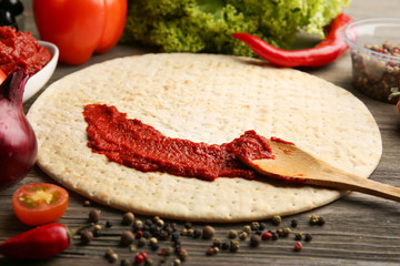 Dough basis and ingredients for pizza in the shape of circle, on the table