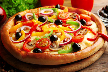 Delicious pizza with vegetables, on wooden table, close-up