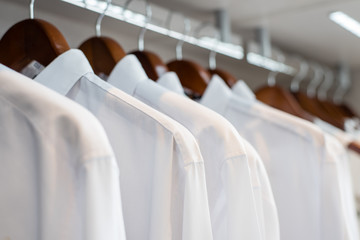 row of white shirts hanged in closet (soft focus)