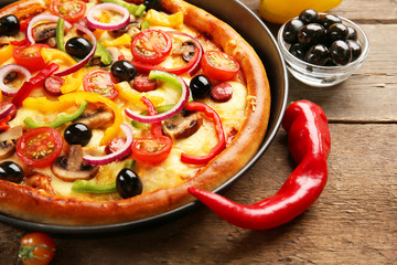 Delicious pizza with vegetables, on wooden table, close-up