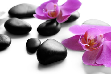 Naklejka na ściany i meble Black spa stones and orchids isolated on white