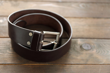 Leather belt with buckle on wooden background