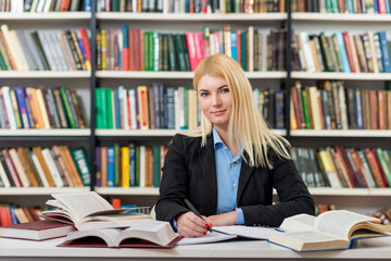 smiling young girl with blonde hair sitting at a desk in the lib