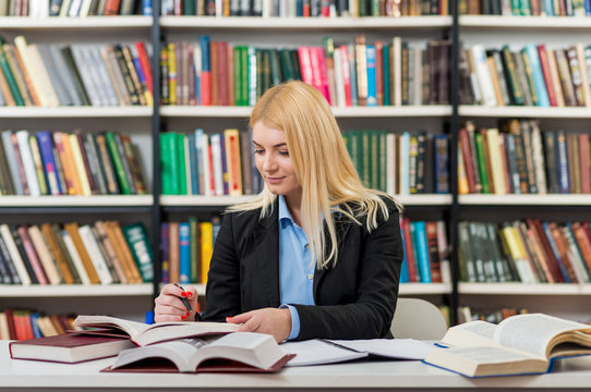 smiling young girl with blonde hair sitting at a desk in the lib