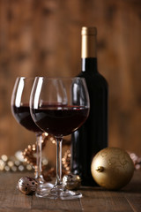 Red wine and Christmas ornaments on wooden table on wooden background
