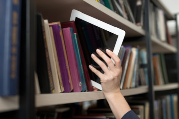 a tablet picked with a hand from a book shelf in the library, a
