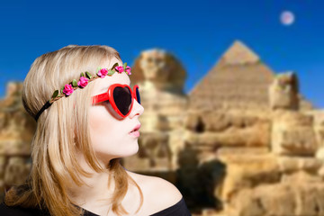 Girl in glasses with retro camera on Egypt pyramid background.