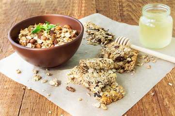Healthy fruit and nuts granola bars, a jar of honey and a bowl o