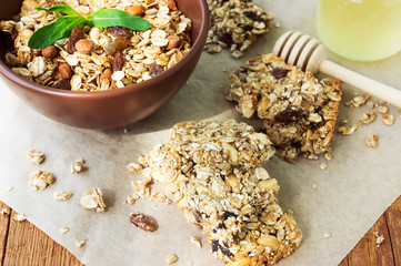 Healthy fruit and nuts muesli bars and a bowl of granola on wood