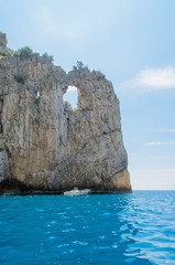 Mountain with hole seen from boat in sea