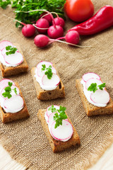 Sandwiches with soft cheese and radish, on sackcloth background