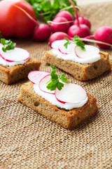 Sandwiches with soft cheese and radish, on sackcloth background