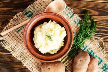 
mashed boiled potato with herbs. milk and spices on a wooden background