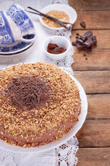Chocolate truffle cake with сrushed peanuts and cacao on a wooden background. Selective focus..